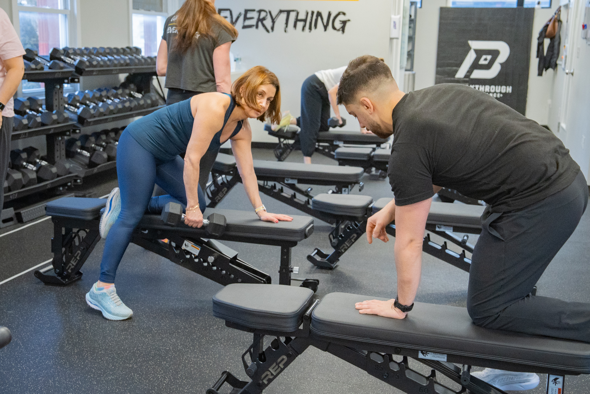 Coach guiding a member through a dumbbell row at Breakthrough Performance